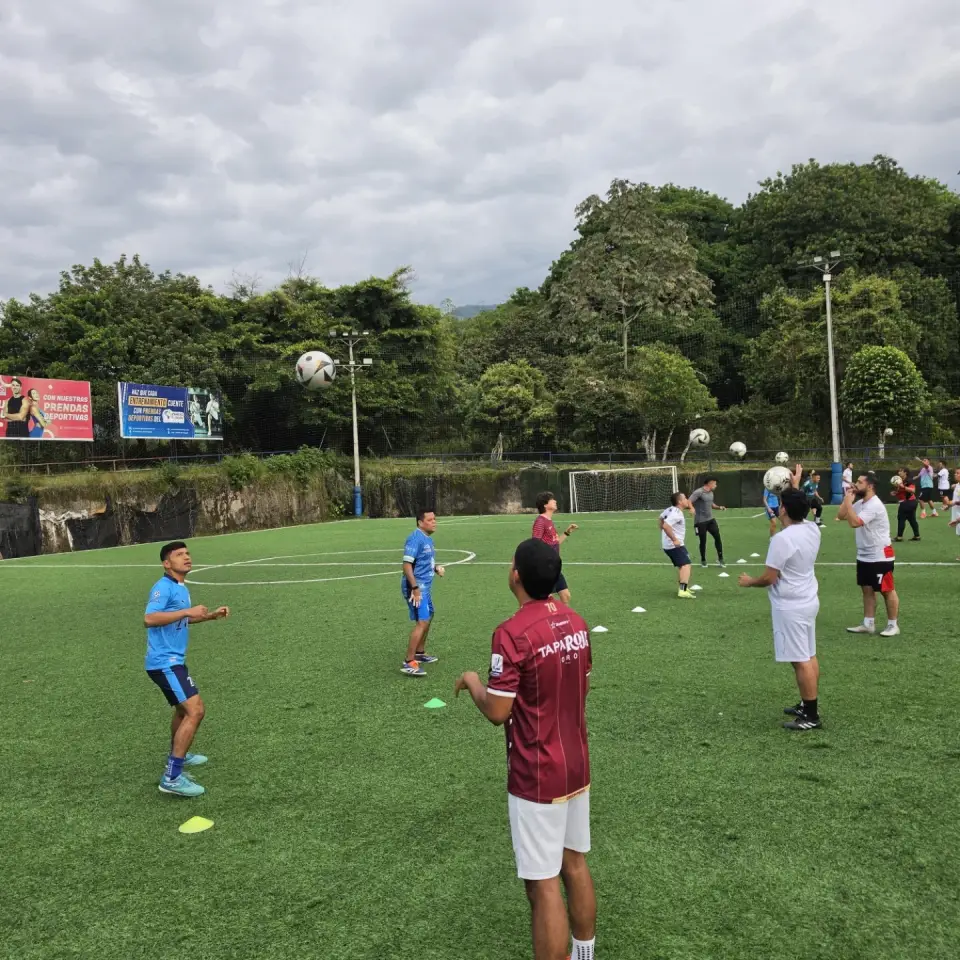 Grupo de adultos entrando en calor con balón en la cancha VyV